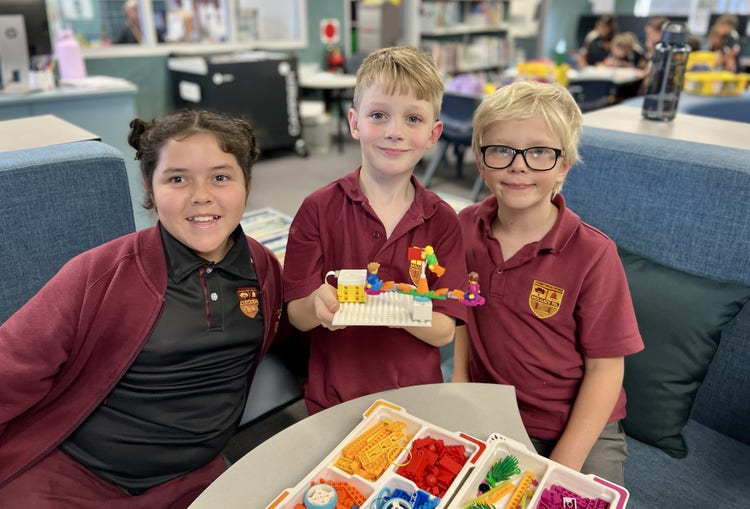 Three students holding lego