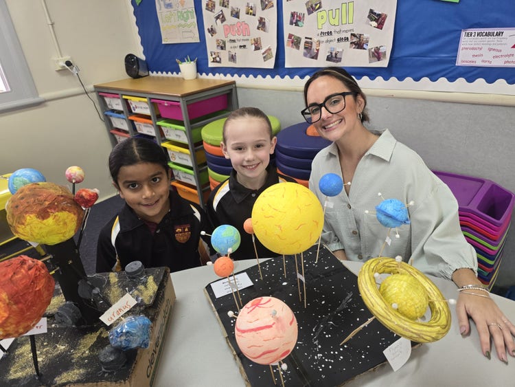 2 students and teacher with solar system models