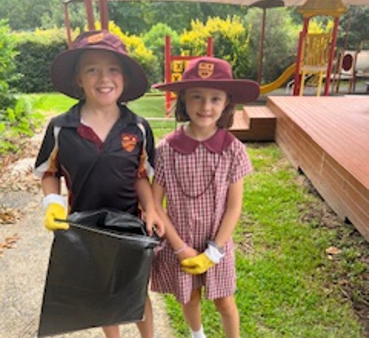 2 girls with gloves in playground collecting rubbish