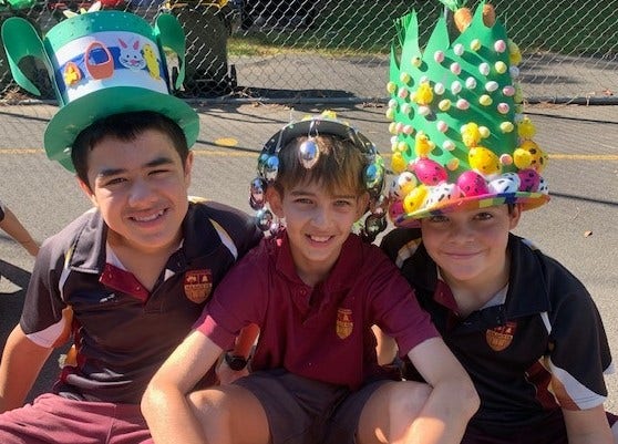 3 boys in Easter hats sitting on ground