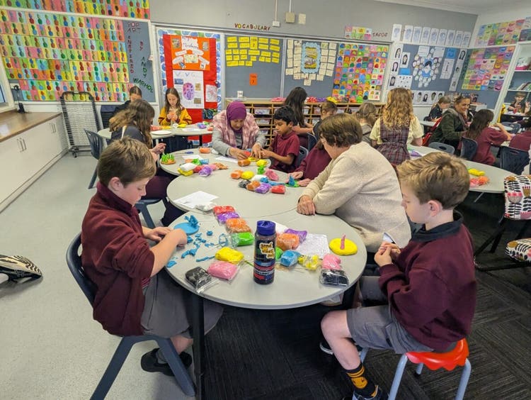 Classroom with students and adults working on sculptures for Education Week